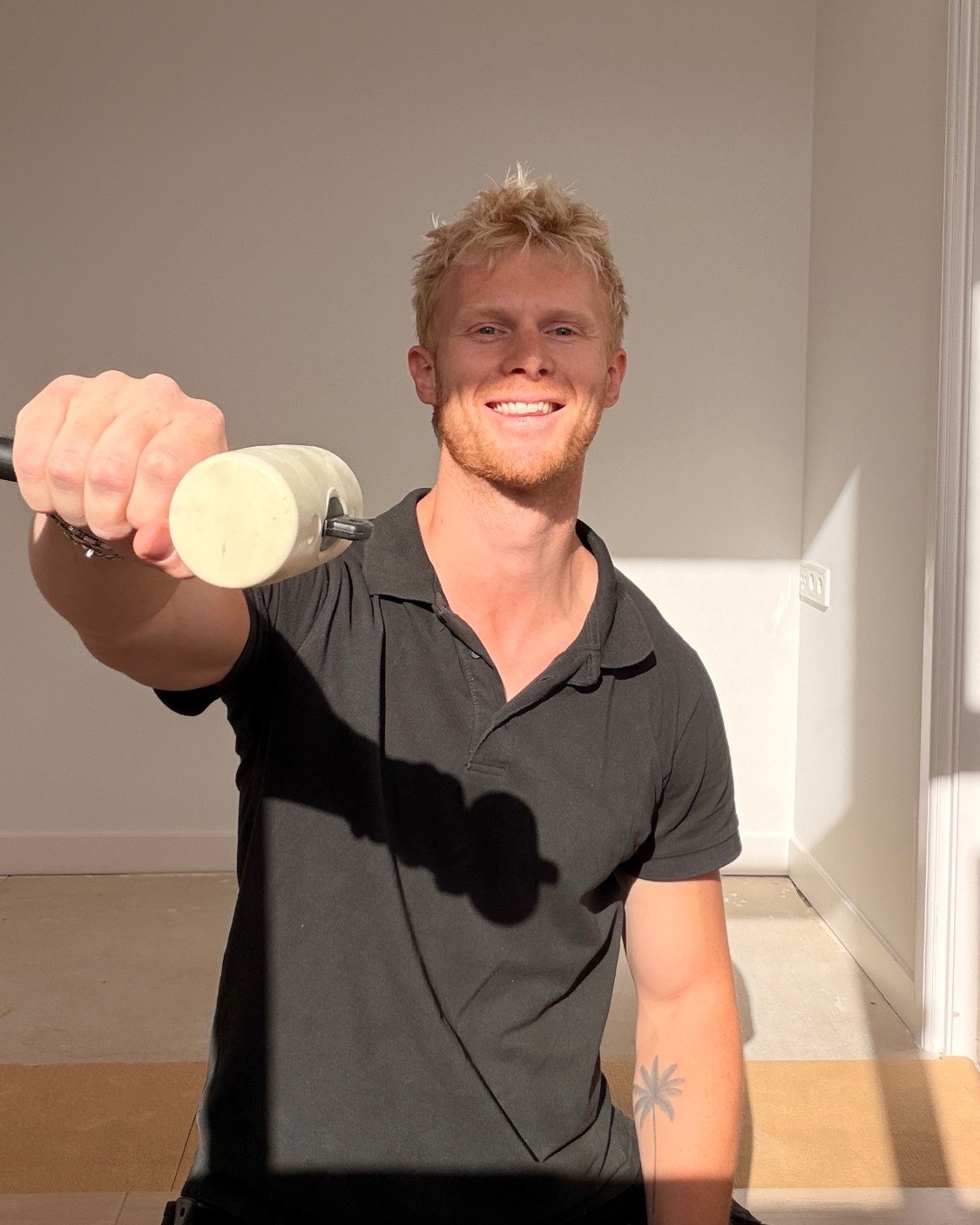 Dennis Bugel van Vloer 't Maar, lachend met een lijmroller in zijn hand in een pas opgeleverde kamer.