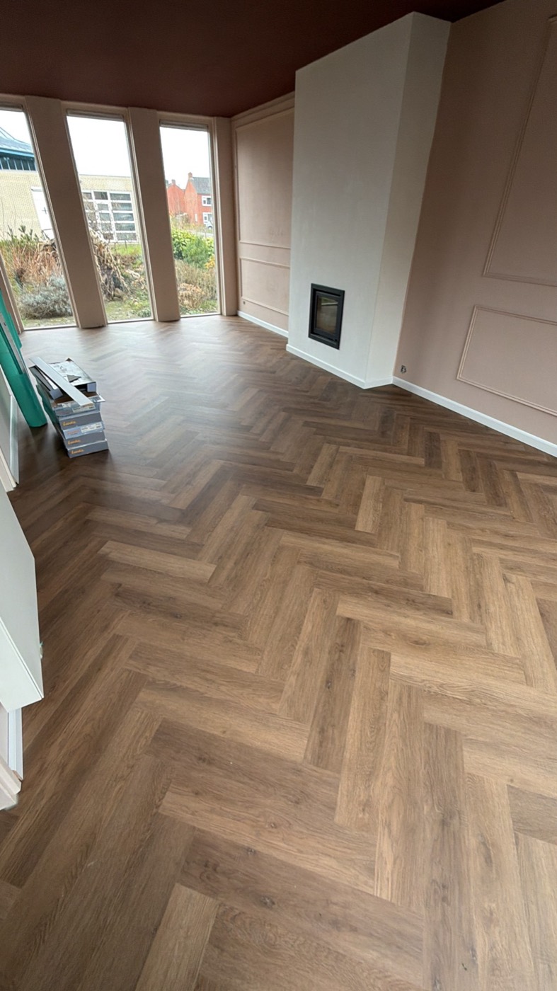 Woonkamer met een PVC-vloer in visgraat, met haard en wandpanelen